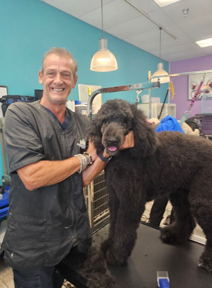 smiling groomer with black dog
